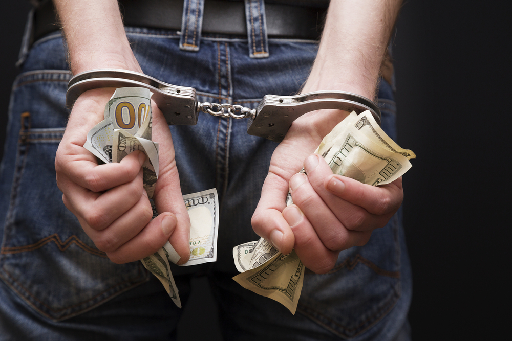 person with handcuffs and cash in hands